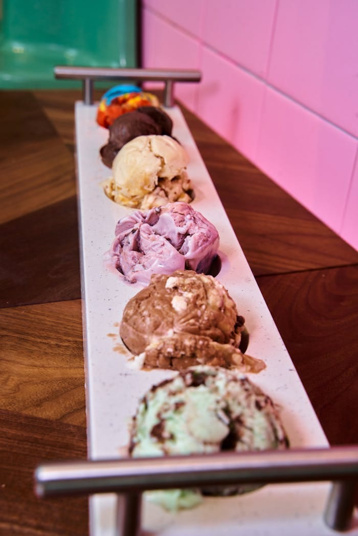 A colorful selection of ice cream scoops arranged on a tray with a vibrant background.