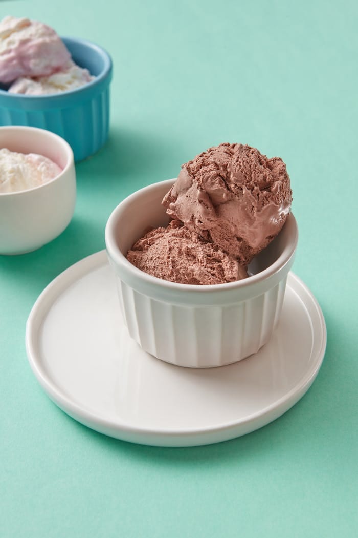 Delicious chocolate ice cream served in ramekins on a pastel backdrop.