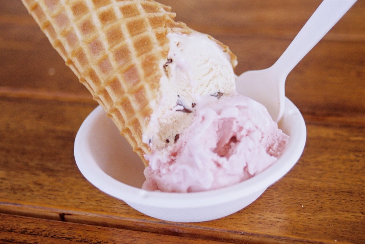 Close-up of a delicious ice cream cone with a waffle texture in a ceramic bowl on a wooden table.
